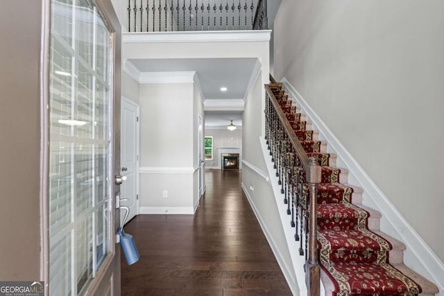 350 Paces Dr, Lithia Springs, GA 30122 - foyer entrance with crown molding, stairway, dark wood-style flooring, a glass covered fireplace, and a high ceiling