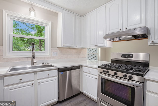 3006 Alberta Dr, Marietta, GA 30062 - kitchen featuring appliances with stainless steel finishes, under cabinet range hood, a sink, white cabinetry, and light countertops