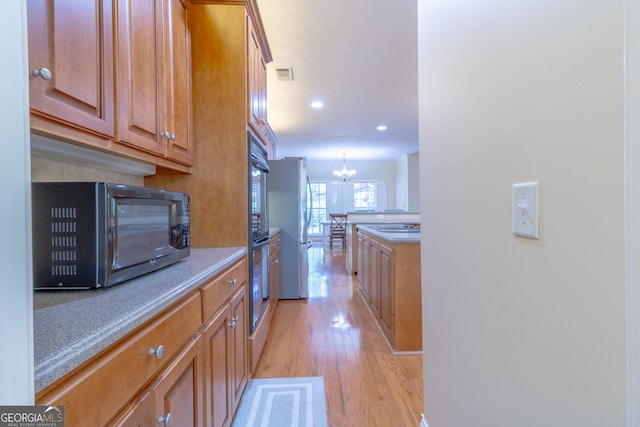 11389 Whitesville Rd, Fortson, GA 31808 - kitchen featuring black appliances, light wood-type flooring, a chandelier, brown cabinetry, and light countertops