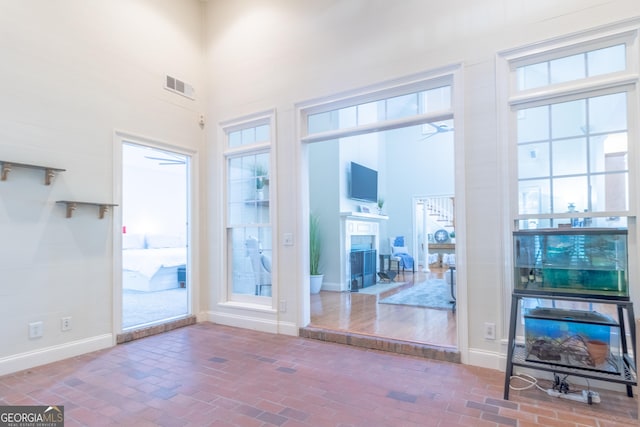 11389 Whitesville Rd, Fortson, GA 31808 - unfurnished living room with a fireplace with flush hearth, brick floors, a high ceiling, ceiling fan, and baseboards