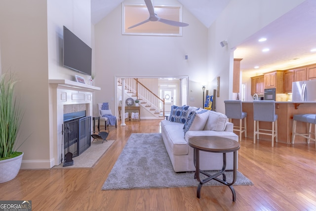 11389 Whitesville Rd, Fortson, GA 31808 - living area with ceiling fan, high vaulted ceiling, a tile fireplace, stairs, and light wood-type flooring
