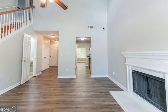 4695 Ravenwood Loop, Union City, GA 30291 - unfurnished living room featuring ceiling fan, dark wood-style floors, baseboards, a towering ceiling, and a fireplace with raised hearth