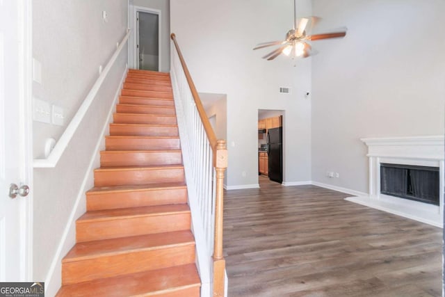 4695 Ravenwood Loop, Union City, GA 30291 - stairway with ceiling fan, a towering ceiling, wood finished floors, a fireplace with raised hearth, and baseboards