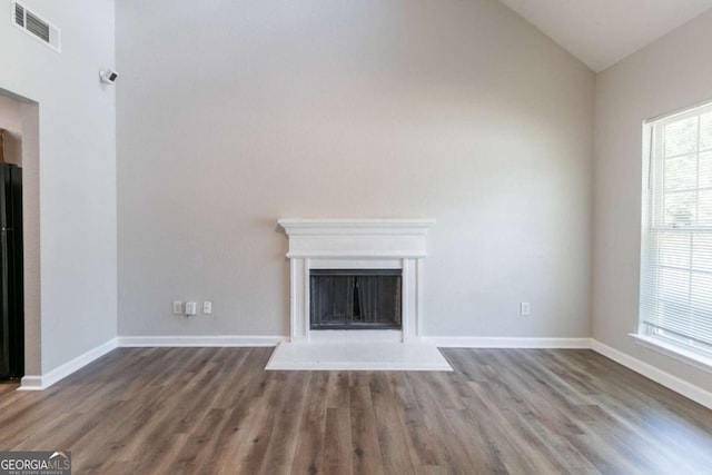 4695 Ravenwood Loop, Union City, GA 30291 - unfurnished living room featuring healthy amount of natural light, wood finished floors, lofted ceiling, a fireplace with raised hearth, and baseboards