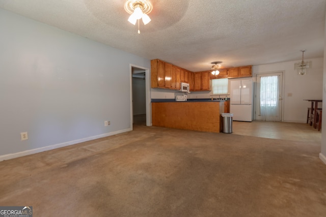 1385 Kinsey Town Rd, Cleveland, GA 30528 - kitchen featuring white appliances, dark countertops, brown cabinets, ceiling fan, and a peninsula