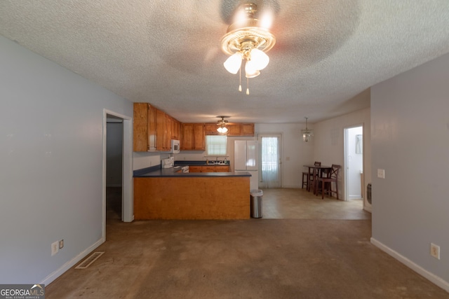 1385 Kinsey Town Rd, Cleveland, GA 30528 - kitchen featuring a ceiling fan, white appliances, a peninsula, brown cabinets, and a textured ceiling