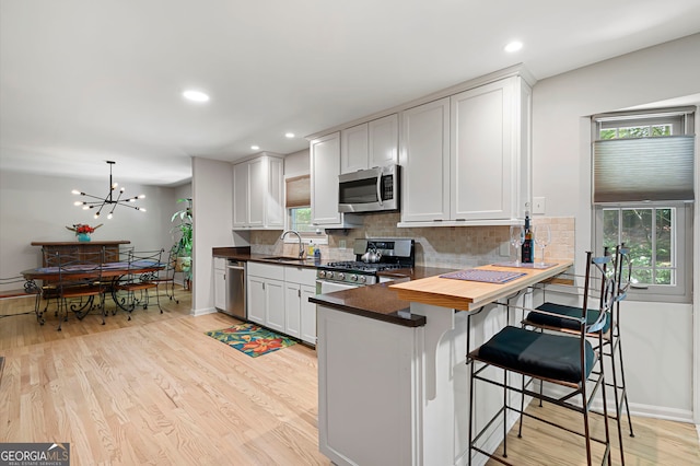 1560 Bubbling Creek Rd NE, Atlanta, GA 30319 - kitchen featuring stainless steel appliances, backsplash, light wood-style floors, healthy amount of natural light, and recessed lighting