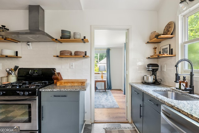 1682 Grace St SE, Atlanta, GA 30316 - kitchen featuring open shelves, appliances with stainless steel finishes, a sink, wall chimney range hood, and decorative backsplash