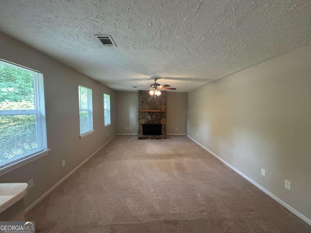 6668 Prinston Cir, Douglasville, GA 30135 - unfurnished living room featuring ceiling fan, baseboards, a stone fireplace, light carpet, and a textured ceiling
