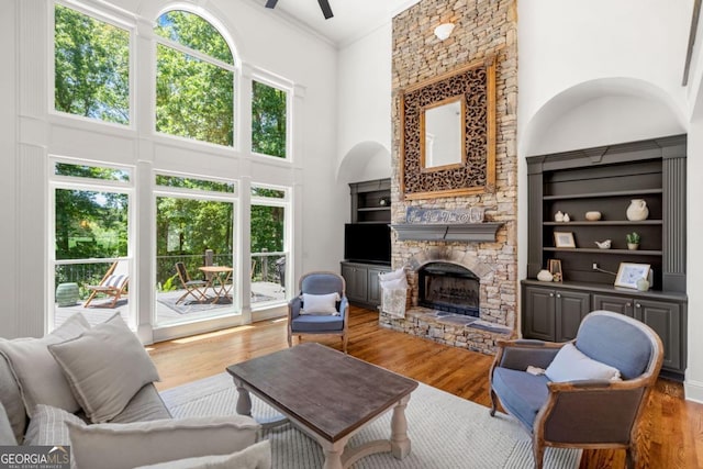 414 Dogwood Way, Canton, GA 30114 - living area featuring a towering ceiling, a stone fireplace, wood finished floors, a ceiling fan, and crown molding