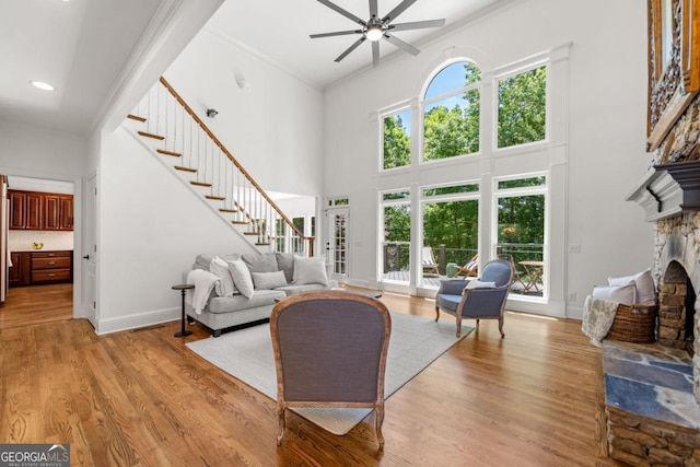 414 Dogwood Way, Canton, GA 30114 - living room with a ceiling fan, a stone fireplace, a towering ceiling, stairway, and light wood-style flooring