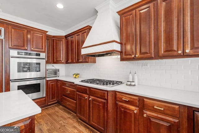 414 Dogwood Way, Canton, GA 30114 - kitchen with stainless steel appliances, custom exhaust hood, light countertops, decorative backsplash, and wood finished floors