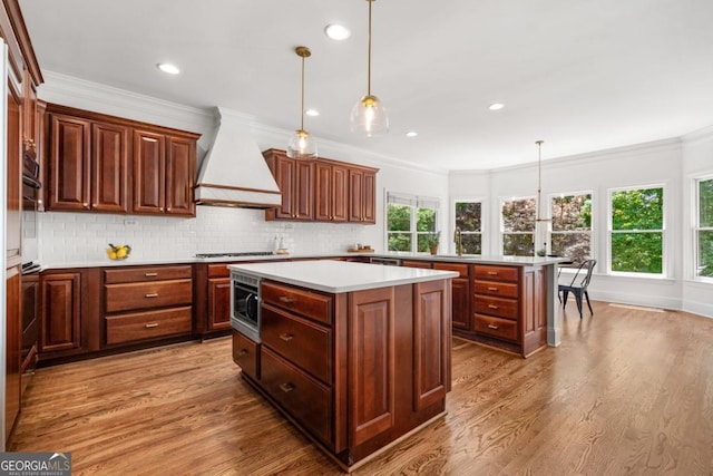 414 Dogwood Way, Canton, GA 30114 - kitchen with custom exhaust hood, a kitchen island, light wood-style floors, stainless steel microwave, and light countertops