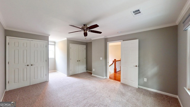 1477 Triple Creek Ct NW, Kennesaw, GA 30144 - unfurnished bedroom featuring light colored carpet, multiple closets, ornamental molding, baseboards, and ceiling fan
