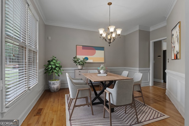 3642 Fowler Rdg, Douglasville, GA 30135 - dining area featuring a chandelier, crown molding, light wood finished floors, and a wainscoted wall