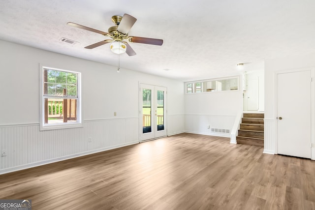 320 Edna Dr, Stockbridge, GA 30281 - unfurnished living room with plenty of natural light, stairs, wood finished floors, a textured ceiling, and a wainscoted wall