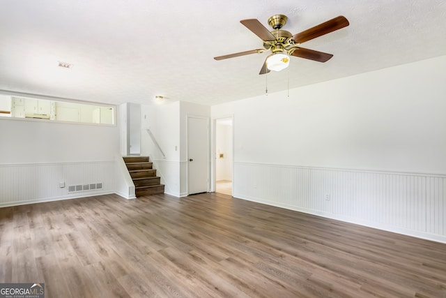 320 Edna Dr, Stockbridge, GA 30281 - unfurnished room featuring wood finished floors, a ceiling fan, stairs, and a wainscoted wall