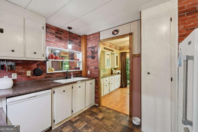 293 Timber Ridge Dr, Athens, GA 30607 - kitchen with dishwasher, brick wall, a sink, white cabinets, and dark countertops