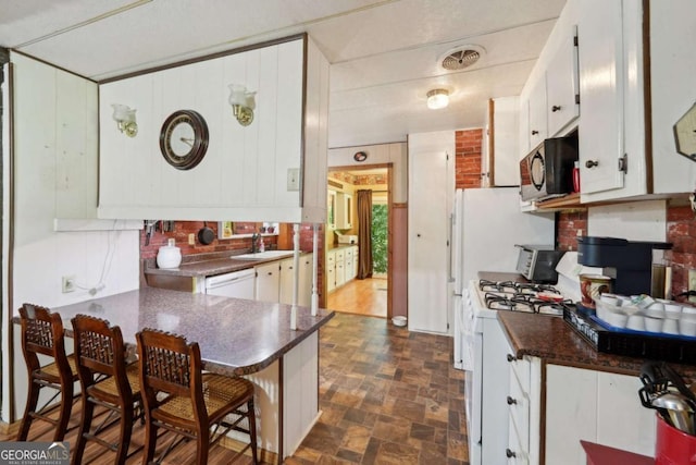 293 Timber Ridge Dr, Athens, GA 30607 - kitchen with dark countertops, white appliances, a sink, white cabinetry, and a peninsula
