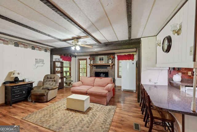 293 Timber Ridge Dr, Athens, GA 30607 - living area with light wood finished floors, a ceiling fan, a fireplace, and wooden walls