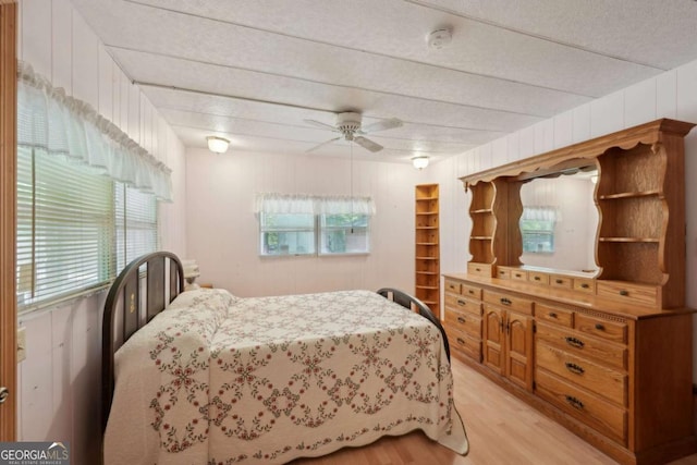 293 Timber Ridge Dr, Athens, GA 30607 - bedroom with light wood-style floors, multiple windows, a ceiling fan, a textured ceiling, and wood walls