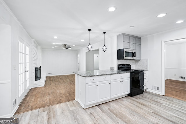 3210 Roseheath Ln, Lithonia, GA 30038 - kitchen with black range with electric stovetop, stainless steel microwave, stone countertops, light wood-style flooring, and recessed lighting