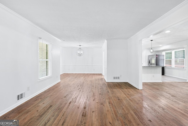 3210 Roseheath Ln, Lithonia, GA 30038 - unfurnished living room featuring a chandelier, crown molding, wood finished floors, and healthy amount of natural light