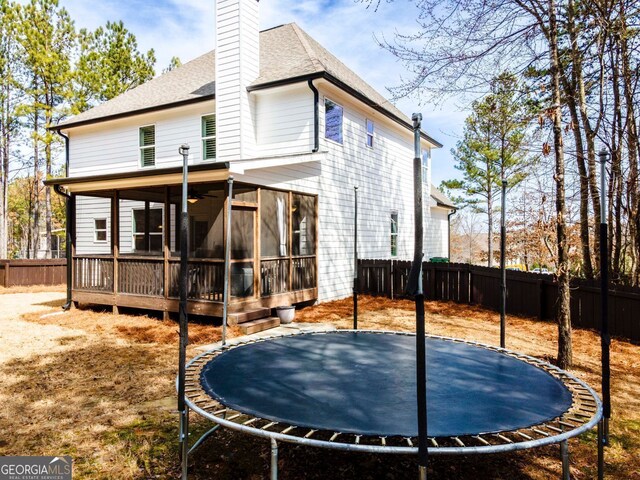15 Jamilee Cv, Cartersville, GA 30120 - rear view of property featuring a trampoline, a fenced backyard, a sunroom, and a chimney