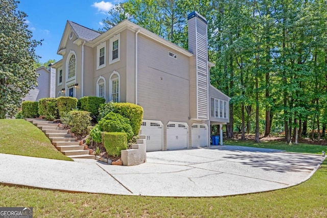 222 Mossy Pl, Alpharetta, GA 30005 - view of side of property featuring a garage, driveway, a chimney, and stairs