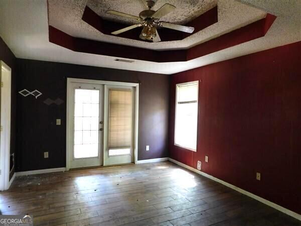 1306 Stonemont Rd, Auburn, GA 30011 - spare room featuring a tray ceiling, baseboards, a textured ceiling, and wood-type flooring