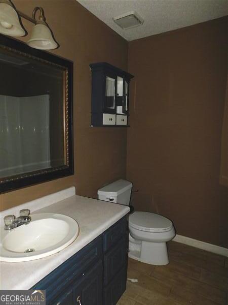 1306 Stonemont Rd, Auburn, GA 30011 - bathroom with toilet, vanity, wood finished floors, and baseboards