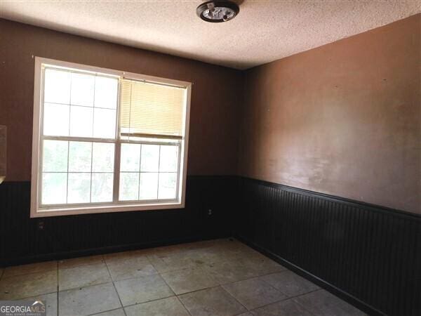 1306 Stonemont Rd, Auburn, GA 30011 - tiled empty room featuring a wainscoted wall and a textured ceiling