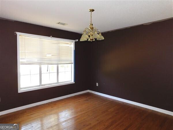 1306 Stonemont Rd, Auburn, GA 30011 - empty room featuring a chandelier, baseboards, and wood finished floors