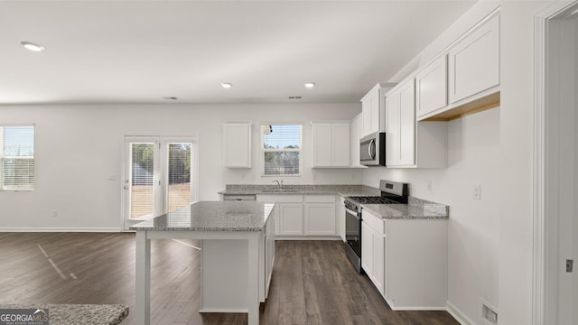 712 Curb Ct, Locust Grove, GA 30248 - kitchen with appliances with stainless steel finishes, a sink, dark wood finished floors, white cabinetry, and a kitchen island