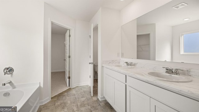 712 Curb Ct, Locust Grove, GA 30248 - bathroom featuring a tub, double vanity, baseboards, a walk in closet, and stone finish floors