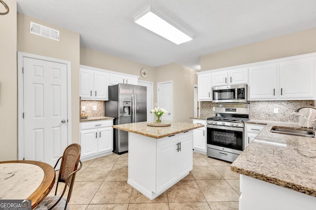 4174 Chatham Crest Ln, Buford, GA 30518 - kitchen featuring stainless steel appliances, a sink, decorative backsplash, a kitchen island, and white cabinets