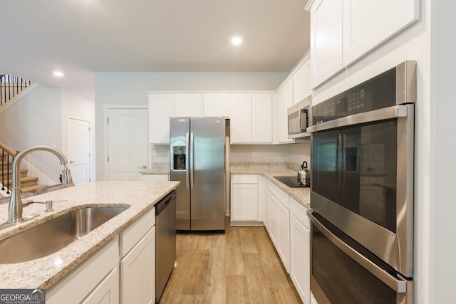 1225 Hibiscus Way, Mcdonough, GA 30253 - kitchen with stainless steel appliances, a sink, light wood-style floors, white cabinets, and recessed lighting