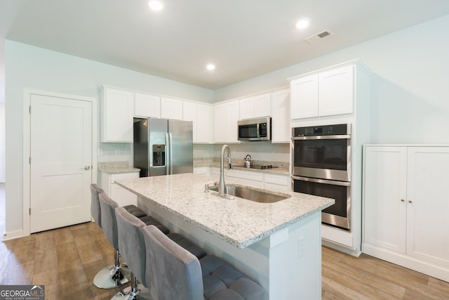 1225 Hibiscus Way, Mcdonough, GA 30253 - kitchen with appliances with stainless steel finishes, a sink, light stone countertops, light wood finished floors, and recessed lighting