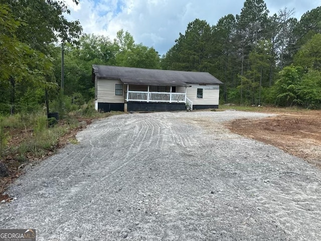 1618 Walls Rd, Sparta, GA 31087 - garage featuring gravel driveway, a porch, and a forest view