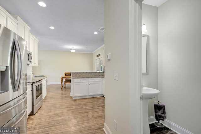 133 Coldwater Ln, Griffin, GA 30224 - kitchen with appliances with stainless steel finishes, white cabinetry, light wood-type flooring, recessed lighting, and a peninsula