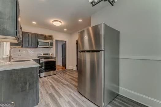 2 E 10th St SW, Rome, GA 30161 - kitchen with appliances with stainless steel finishes, a sink, light wood-style flooring, tasteful backsplash, and light countertops