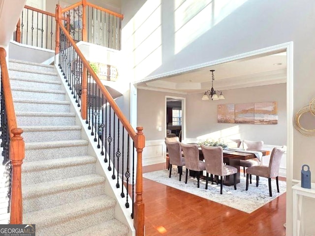 779 Avonley Creek Trce, Buford, GA 30518 - staircase with wood finished floors, a chandelier, ornamental molding, and a wainscoted wall
