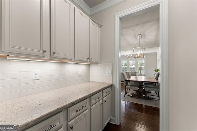 3317 Sweetleaf Ln, Buford, GA 30519 - kitchen featuring dark wood-style flooring, a chandelier, light stone counters, ornamental molding, and decorative backsplash