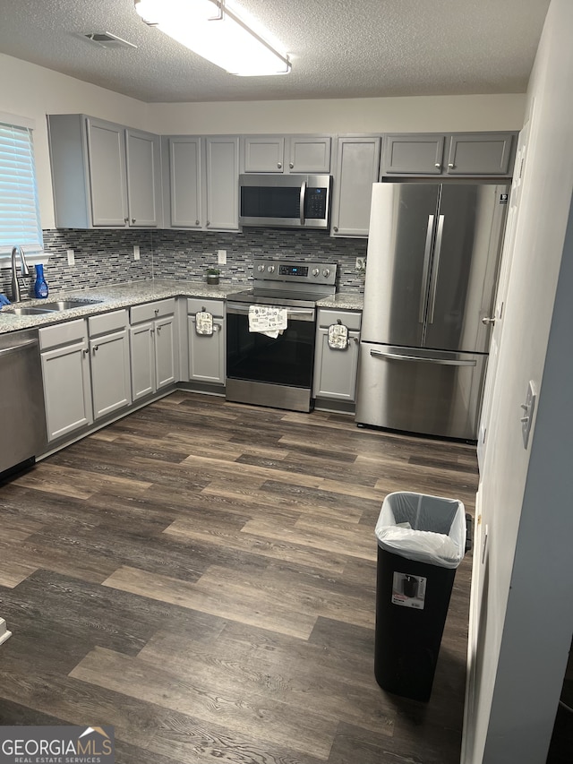 1263 Brookstone Rd, Atlanta, GA 30349 - kitchen with appliances with stainless steel finishes, a sink, dark wood-type flooring, decorative backsplash, and a textured ceiling