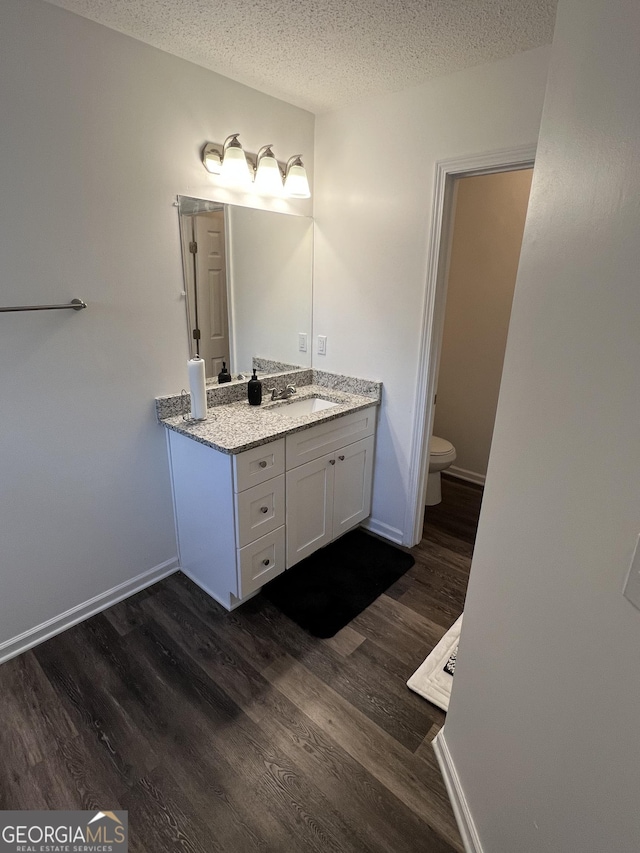 1263 Brookstone Rd, Atlanta, GA 30349 - bathroom with vanity, a textured ceiling, wood finished floors, toilet, and baseboards