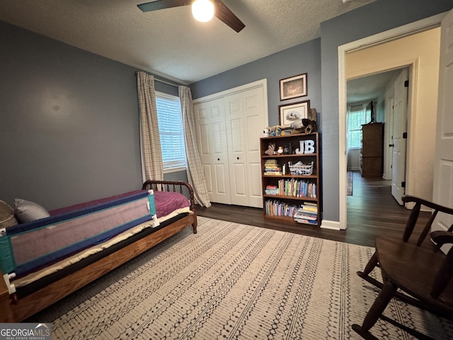 353 Lewis Cir, Commerce, GA 30529 - bedroom featuring a textured ceiling, multiple windows, dark wood-style flooring, a closet, and baseboards