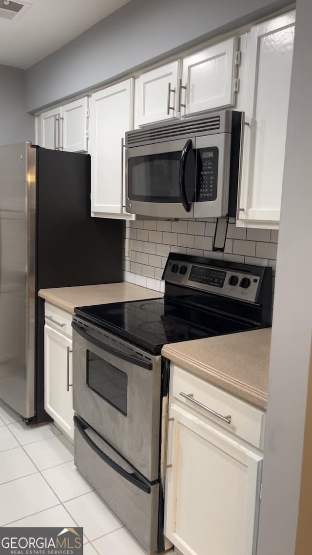 2119 Pine Heights Dr NE, Atlanta, GA 30324 - kitchen featuring appliances with stainless steel finishes, backsplash, light tile patterned flooring, and white cabinetry