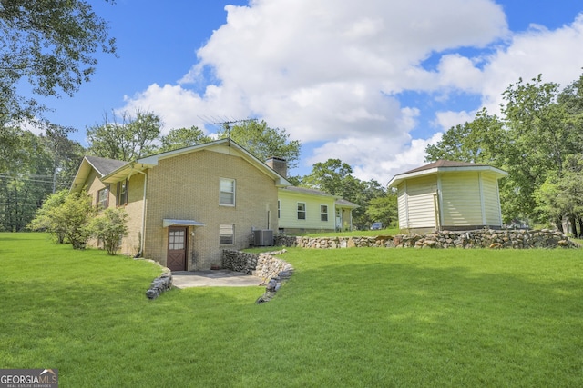 4911 Old Douglasville Rd, Lithia Springs, GA 30122 - rear view of house featuring brick siding, a yard, a chimney, a patio, and central AC unit