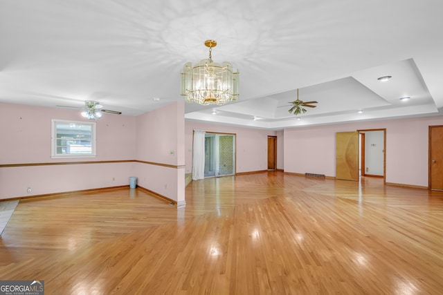 4911 Old Douglasville Rd, Lithia Springs, GA 30122 - unfurnished living room featuring a tray ceiling, ceiling fan, baseboards, a chandelier, and light wood finished floors