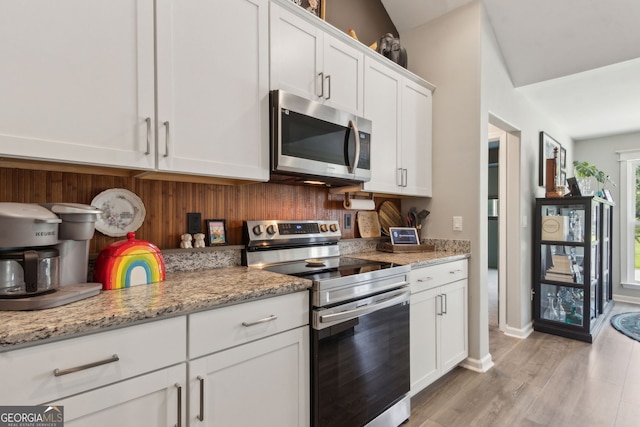 102 Bowline Ln, Kingsland, GA 31548 - kitchen featuring appliances with stainless steel finishes, white cabinets, light wood-style flooring, light stone countertops, and baseboards